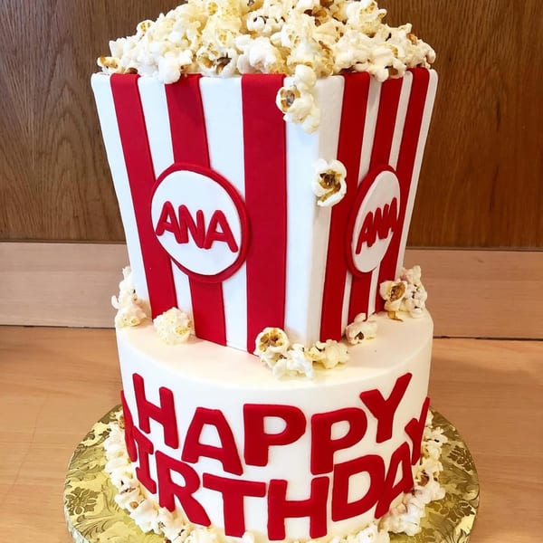 Two-tiered birthday cake shaped like a popcorn box, with "Happy Birthday" in red letters.