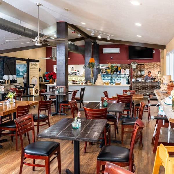 Spacious interior of Mama's Bistro Cafe and Bakery with wooden tables, red chairs, and a counter.